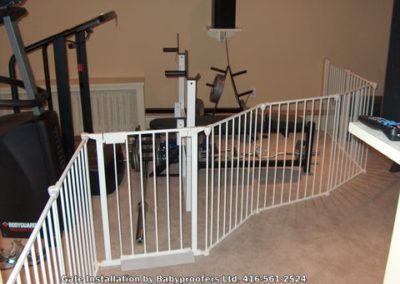 White baby gate installed to keep children from workout equipment.