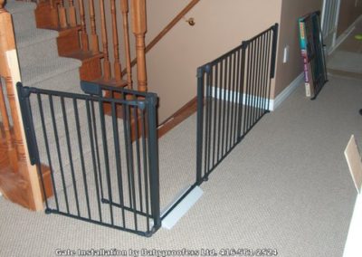 Dark green baby gate designed to restrict access to stairs going up and down.