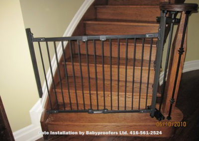 Baby gate attached to metal railings using specialty clamps.