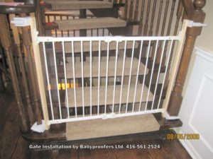 White safety gate installed with clamps instead of mounting holes.