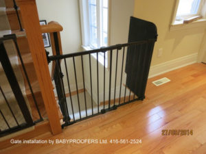 Black baby gate installed with fixed panel on the right.