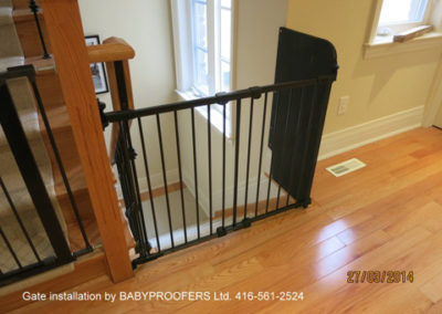 Black baby gate installed with fixed panel on the right.