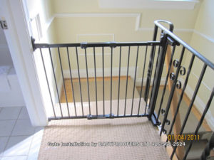Baby gate installed between wall and metal railing.