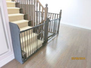 Two grey baby gates installed with one using extension panel on the left.