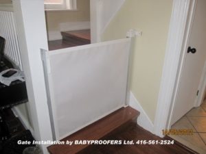 Retractable baby gate installed at the bottom of the stairs.