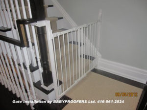 White baby gate installed using newel post clamps.