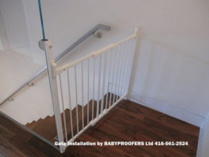 White baby gate attached to glass wall.