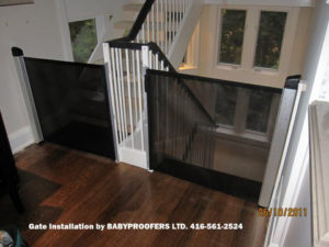 Black retractable baby gates installed on either side of stair openings.