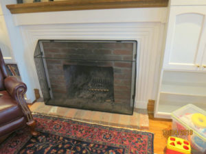 Black child safe fire screen installed in front of natural fireplace.