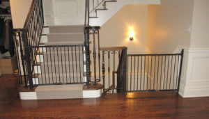 Pair of black baby gates installed between wall and railings.