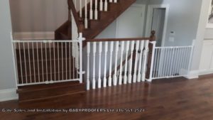 2 white baby gates installed across up and down stairs to same floor.