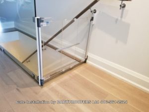 Crystal clear baby gate installed beside clear glass panel.